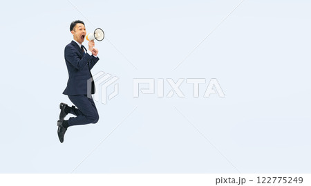 拡声器を持ってジャンプするミドル男性ビジネスパーソンの全身写真 122775249