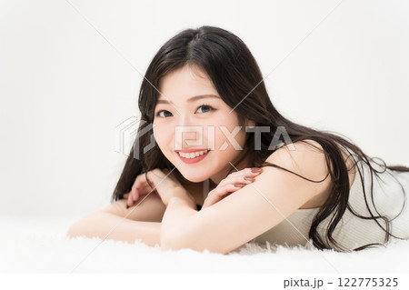 ビューティーイメージ　笑顔で寝そべる若い女性 　カメラ目線 122775325