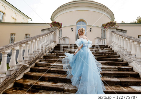 Elegant Woman in a Flowing Blue Gown Walking Down the old stone Stairs. Back view. Elegant Woman in a Flowing Blue Gown Walking Down the old stone Stairs. Back view. 122775787