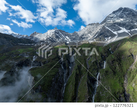 Aerial view of beautiful high altitude snow capped mountain and forest landscape 122776321