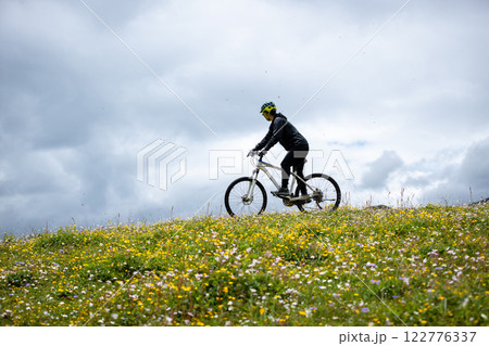 Riding mountain bike on flowering grassland mountain top Riding mountain bike on flowering grassland mountain top 122776337