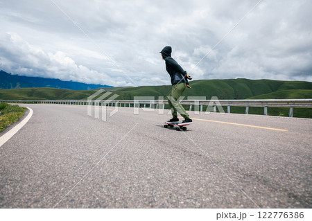Skateboarder skateboarding on the mountain road 122776386