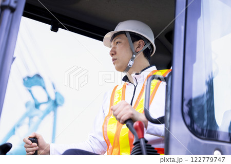工事現場で働く作業員　クレーン車の運転をする男性 122779747