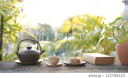 Metal tea pot and tea cup and Crispy Rice Cracker on wooden table, cozy workspace 122780123