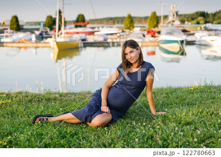 Beautiful Pregnant Woman Sitting Near Marina on Peaceful Summer Day 122780663
