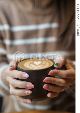 young woman drinking cappuccino with heart latte art in winter, female with Christmas Nail art manicure and hand holding and enjoying a cup of coffee at home in the morning young woman drinking cappuccino with heart latte art in winter, female with Christmas Nail art manicure and hand holding and enjoying a cup of coffee at home in the morning 122781124