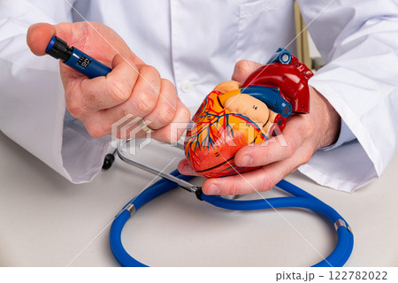 Doctor holding injection syringe and heart in hands. Heart attack, disease or vaccination concept Doctor holding injection syringe and heart in hands. Heart attack, disease or vaccination concept 122782022