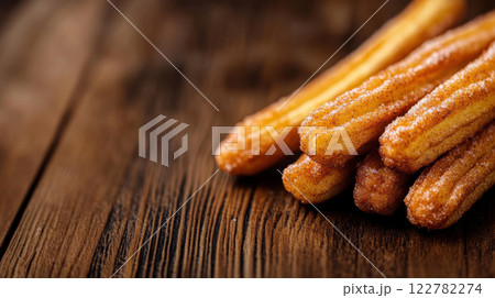 Freshly fried churros coated in cinnamon sugar on wooden surface Freshly fried churros coated in cinnamon sugar on wooden surface 122782274