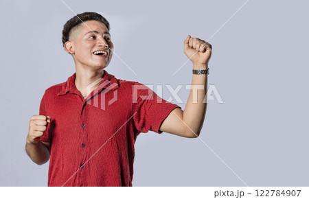 Guy raising hands in victory sign, latin man raising hands in victory on isolated background 122784907