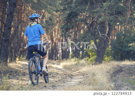 woman cyclist rides in the pine forest on a mountain bike. 122784913