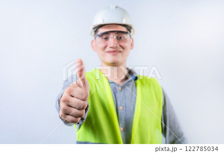 Smiling young engineer gesturing approval with thumb. Cheerful engineer giving thumbs up to the camera isolated Smiling young engineer gesturing approval with thumb. Cheerful engineer giving thumbs up to the camera isolated 122785034