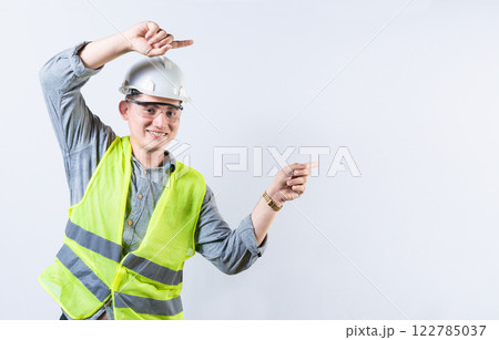 Portrait of smiling engineer pointing aside isolated. Handsome engineer pointing an advertisement isolated 122785037
