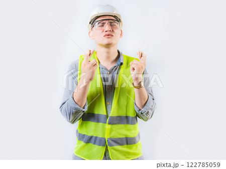 Portrait of young engineer making a wish. Handsome engineer crossing fingers making a wish 122785059