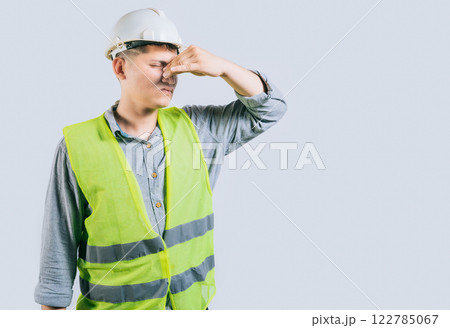 Man engineer covering her nose from a bad smell isolated isolated. Displeased young engineer holding her nose isolated Man engineer covering her nose from a bad smell isolated isolated. Displeased young engineer holding her nose isolated 122785067