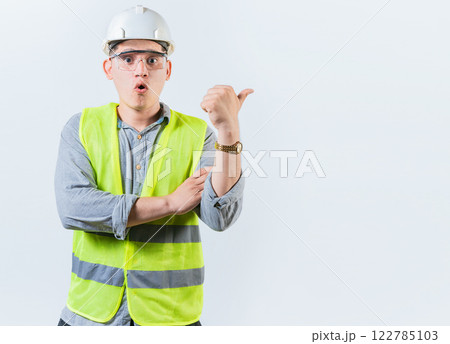 Portrait of surprised engineer man pointing side. Amazed engineer pointing advertising to side isolated. Construction worker pointing at an advertisement side 122785103