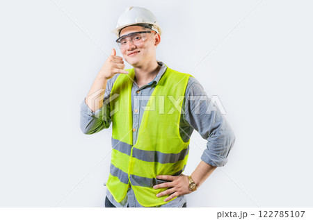 Portrait of young engineer making call gesture isolated. Handsome engineer making call gesture with fingers 122785107
