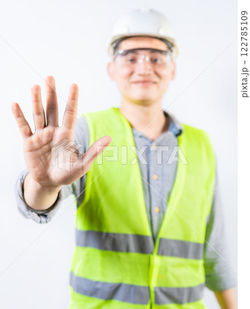 Young engineer counting number five isolated. Smiling engineer showing number five with hand isolated 122785109