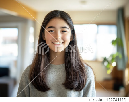 AI生成画像　リビングでカメラを見て笑う黒いロングヘアの10代の女の子のポートレート 122785335