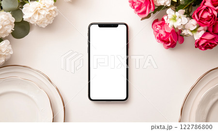 花のテーブルセッティングにスマートフォンを置いたミニマリストな結婚式招待状のモックアップ 花のテーブルセッティングにスマートフォンを置いたミニマリストな結婚式招待状のモックアップ 122786800