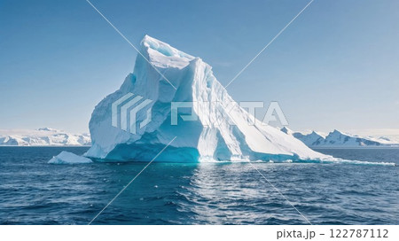 A colossal iceberg floats peacefully in icy blue waters, its jagged edges illuminated by sunlight. The stunning frozen landscape symbolizes nature raw power and fragility A colossal iceberg floats peacefully in icy blue waters, its jagged edges illuminated by sunlight. The stunning frozen landscape symbolizes nature raw power and fragility 122787112