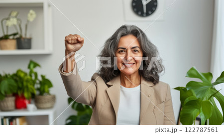 Middle aged hispanic woman with raised fist of empowerment, strength and women solidarity, International Womens Day concept 122787561