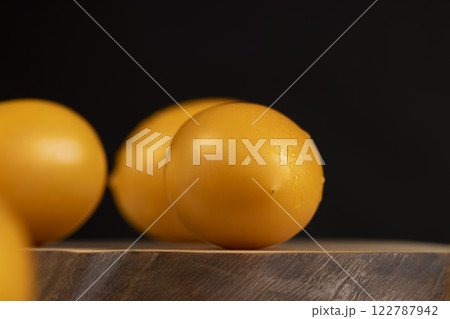 a large number of ripe orange tomatoes on a walnut board 122787942