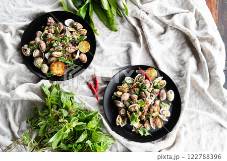 Clams and mussels are artfully arranged with herbs against a green backdrop. 122788396