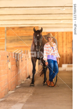 Cowgirl standing next to brown horse friend 122788495