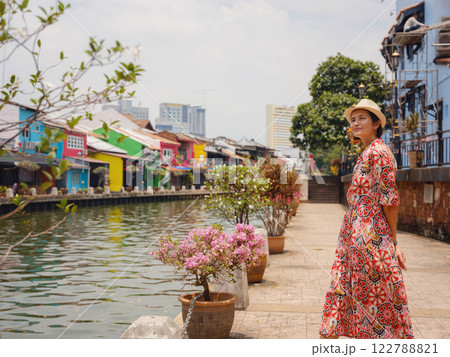 woman in dress and hat exploring vibrant streets of Malacca, Malaysia. 122788821