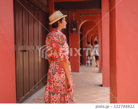 woman in dress and hat exploring vibrant streets of Malacca, Malaysia. 122788822