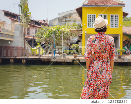 woman in dress and hat exploring vibrant streets of Malacca, Malaysia. 122788823
