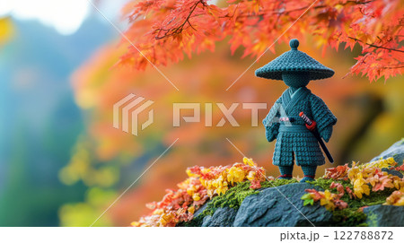 banner with a figurine of a samurai crocheted from wool against the background of an autumn forest, handmade toys 122788872