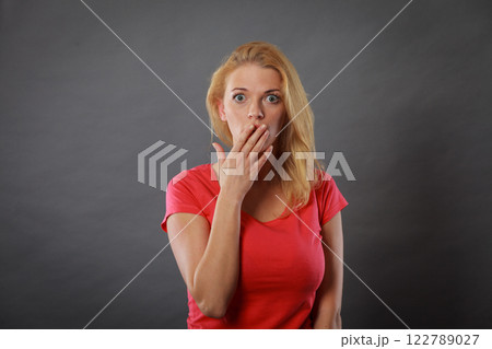 Shocked woman holding hand on lips 122789027