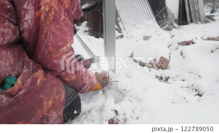 A person working on construction in a snowy environment, demonstrating resilience and determination. 122789050