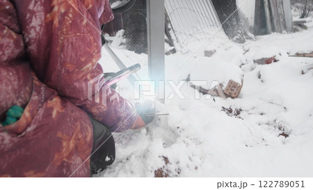 A skilled individual employs tools in a snowy landscape, showcasing the unique challenges of winter work A skilled individual employs tools in a snowy landscape, showcasing the unique challenges of winter work 122789051