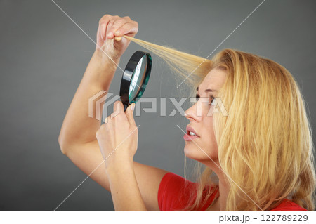 Woman looking at hair through magnifying glass Woman looking at hair through magnifying glass 122789229