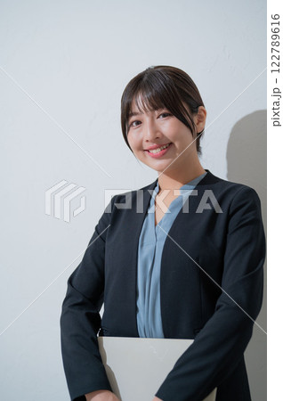 白背景でパソコンを持って微笑む日本人女性 122789616