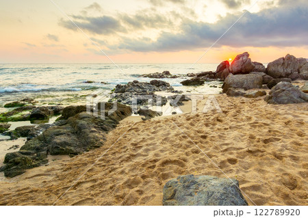 summer vacation landscape at the beach. dramatic seascape at sunrise. calm wave washing the coast with sand and rocks. beautiful view of sky with sun and cloud above horizon 122789920