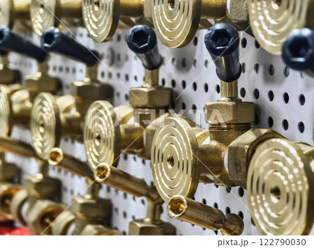 Detailed view of brass valves and fittings arranged on a pegboard in a workshop setting Detailed view of brass valves and fittings arranged on a pegboard in a workshop setting 122790030