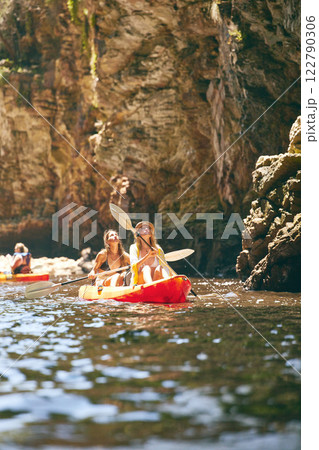 Travel, kayak and female friends on an adventure while on a lake or sea with a mountain view in nature. Women having fun while traveling and enjoying water activity while on a vacation holiday trip 122790306