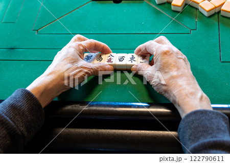 電動麻雀卓で麻雀をしているシニア男性の手元 122790611