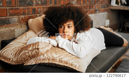 Sad, tired and depressed African woman thinking with burnout, anxiety and depression on the sofa in the living room in home. Girl with mental health problem with idea, in fear and trauma in house 122790617