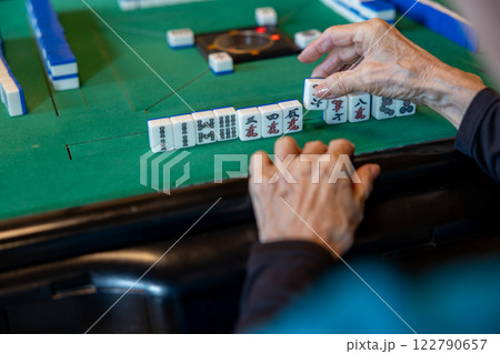 電動麻雀卓で麻雀をしているシニア女性の手元 122790657
