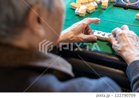電動麻雀卓で麻雀をしているシニア男性の手元 122790709
