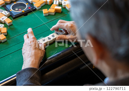 電動麻雀卓で麻雀をしているシニア男性の手元 122790711
