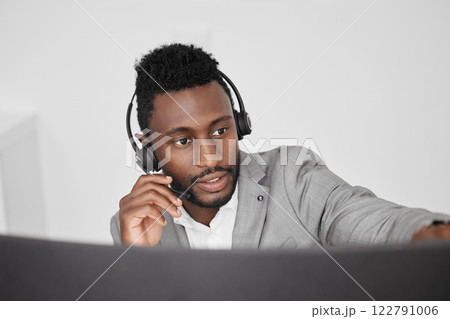 Call center, customer service and crm representative wearing headset while consulting with customer in telemarketing company. Serious black man in contact us and sales support working on a computer Call center, customer service and crm representative wearing headset while consulting with customer in telemarketing company. Serious black man in contact us and sales support working on a computer 122791006