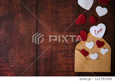 An envelope with an envelope and hearts on a wooden background An envelope with an envelope and hearts on a wooden background 122791090