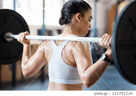Fitness, motivation and workout of a woman at the gym on intense weightlifting training and exercise for arm muscle. Strong female personal trainer or coach exercising with heavy barbell indoors. 122791216