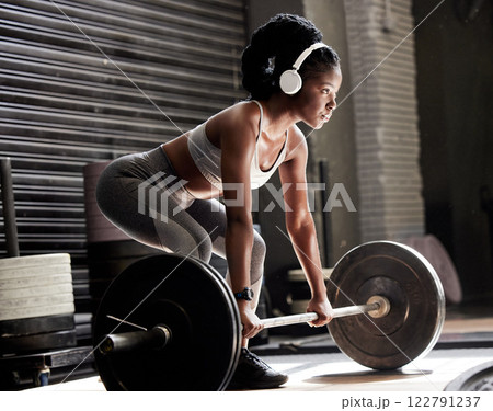 Power, fitness and headphones of a woman with barbell weight lift exercise, workout or training in wellness gym. Sports black woman listening to motivation music for muscle, strength and health Power, fitness and headphones of a woman with barbell weight lift exercise, workout or training in wellness gym. Sports black woman listening to motivation music for muscle, strength and health 122791237