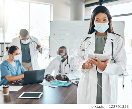 Doctor with covid face mask and tablet, healthcare worker and medical expert doing research in meeting at hospital and planning schedule online. Portrait of African employee consulting on the web 122791338